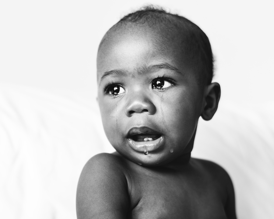 Black and white image of a black baby crying due to a toothache